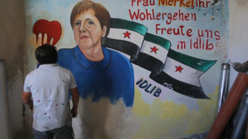 Aziz Asmar se despide de la canciller alemana con un retrato en un muro bombardeado por el régimen de Asad. 